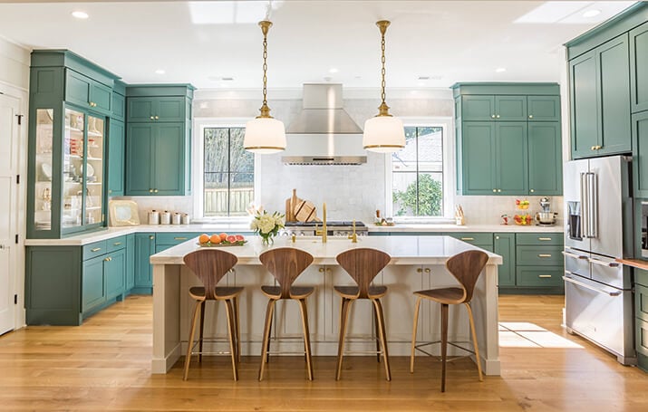 Open kitchen with green cabinets, white countertops, and natural light.