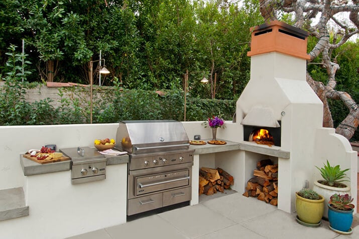 Outdoor kitchen with concrete countertop and pizza oven.