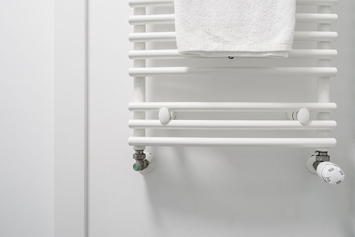 A white towel hanging on an over the door towel rack.