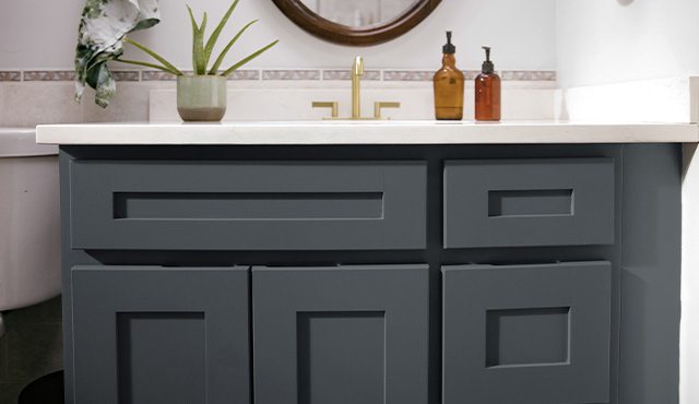 Painted gray bathroom cabinets with white countertops.