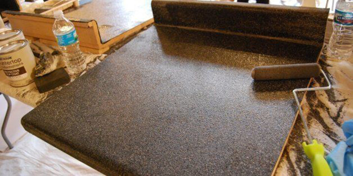 Painting a faux granite countertop with a paint roller.