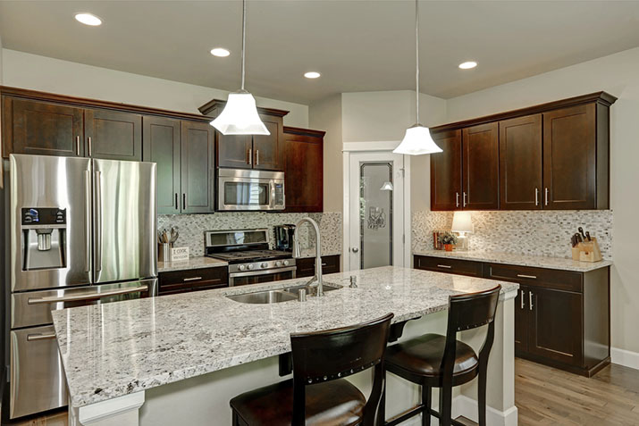 A warm, attractive kitchen with stainless appliances and pendant lights.
