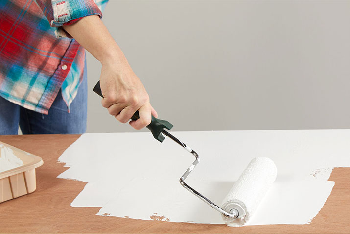 Person priming laminate countertops with a paint roller.