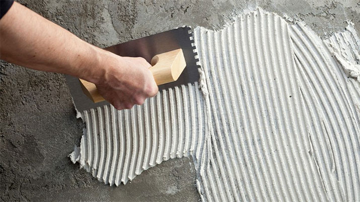 Person using trowel to apply mortar to wall.
