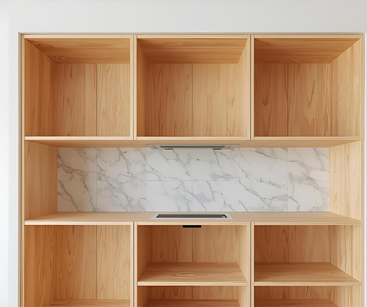 Plywood kitchen cabinets before the doors are installed against a faux marble backsplash.