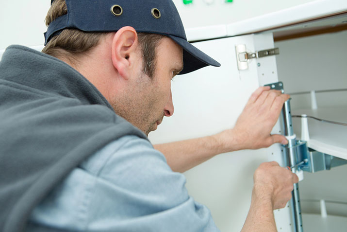Professional carpenter installing kitchen cabinets.