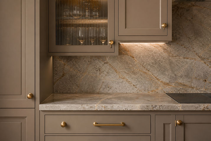 Quiet luxury kitchen detail with mushroom-toned matte cabinets, unlacquered brass hardware, and honed quartzite countertop.