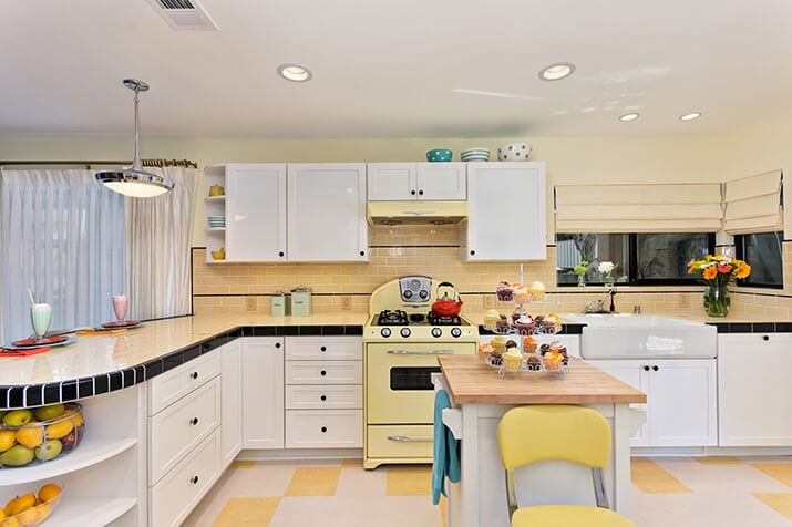 Retro kitchen with yellow tile countertops with checkered flooring.