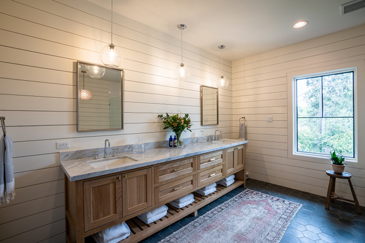 Rustic bathroom with double vanity featuring mirrors and shiplap.