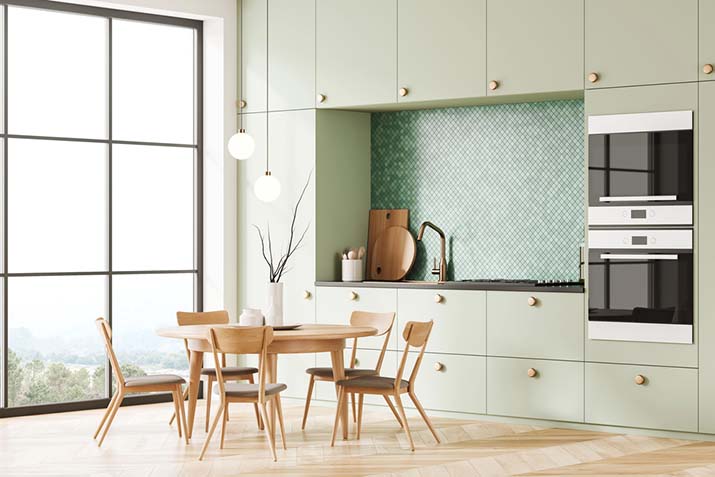 Sage green cabinets in a bright small kitchen.
