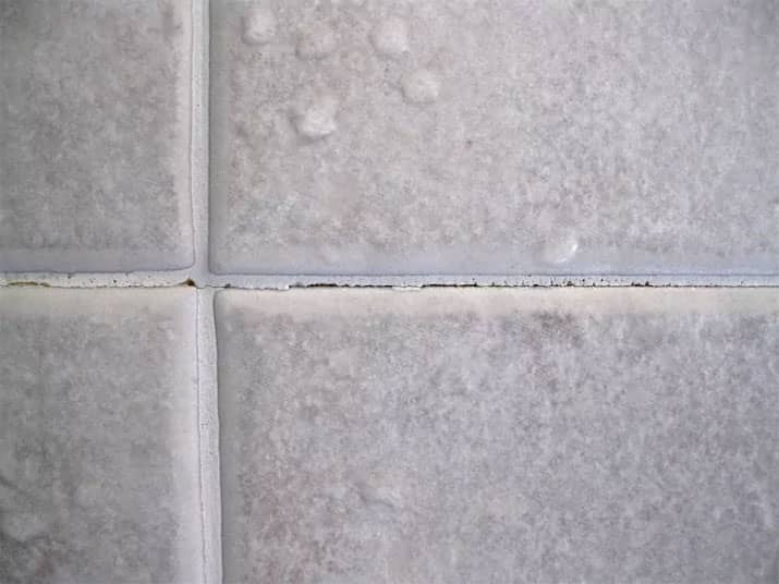 Shower tile grout lines with cracks.