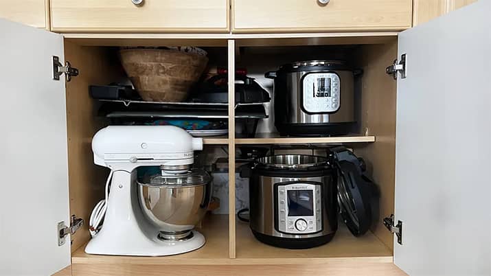 Small kitchen appliances are stored in the lower cabinets.