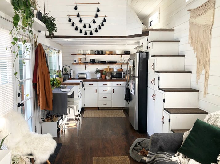 Small kitchen in a tiny home with open shelving for glassware and dishes.