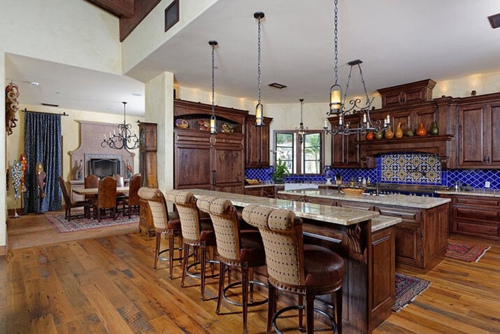 Spanish-style kitchen with dark cabinetry contrasted with a vibrant blue backsplash.