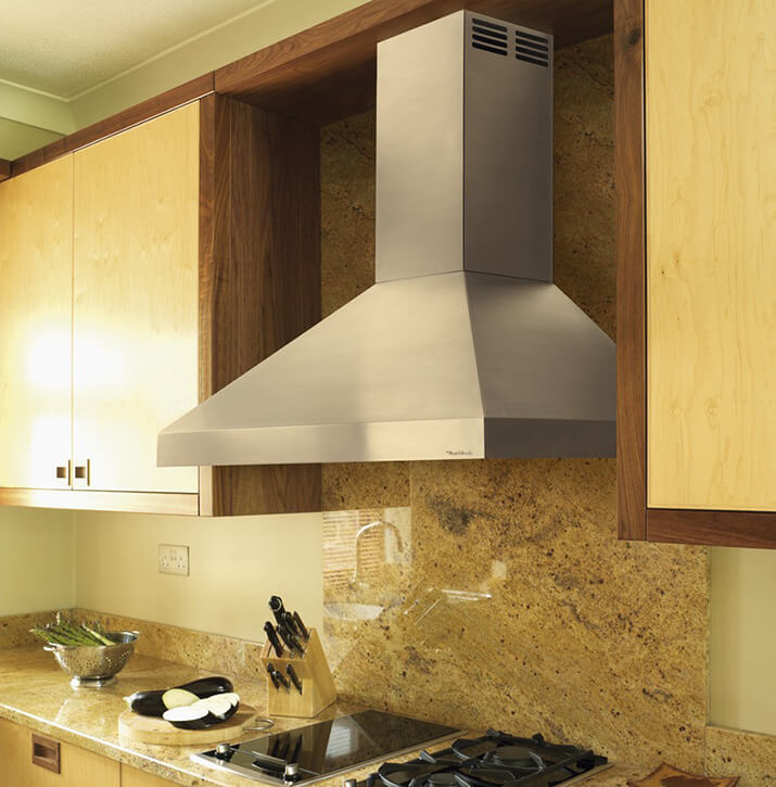 Stainless steel kitchen hood design over a marble backsplash.