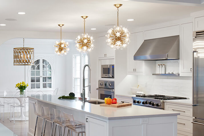 Statement light fixtures over the island in a white kitchen.
