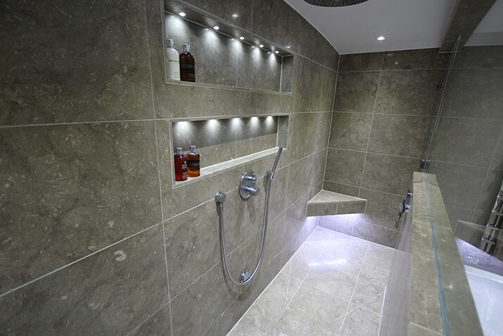 Stone shower with corner bench and LED lighting.