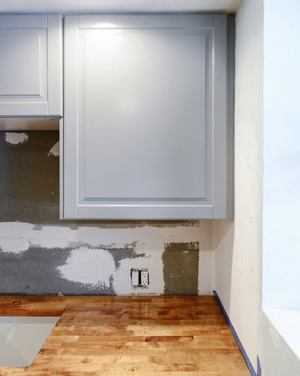 Thin cabinet filler strip installation against a wall before backsplash is finished.