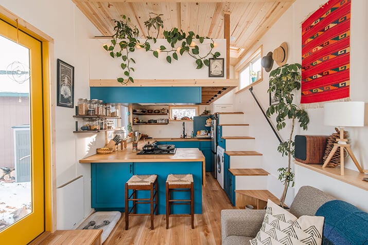 Tiny home kitchen with blue cabinets, wood countertops, and open shelving.