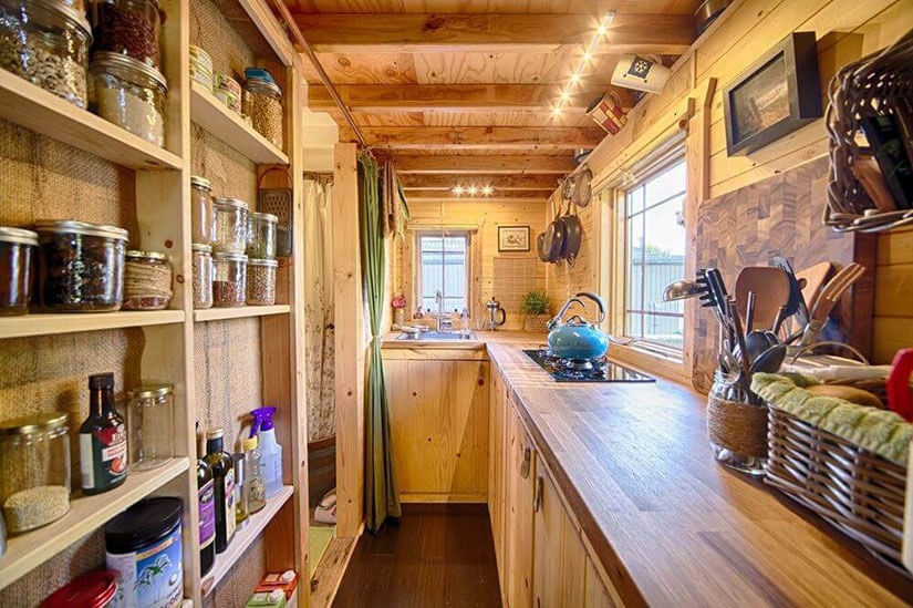 A tiny kitchen with a wall of shallow shelves in this mountain retreat.
