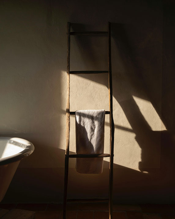 Dimly lit bathroom with towels on ladder.