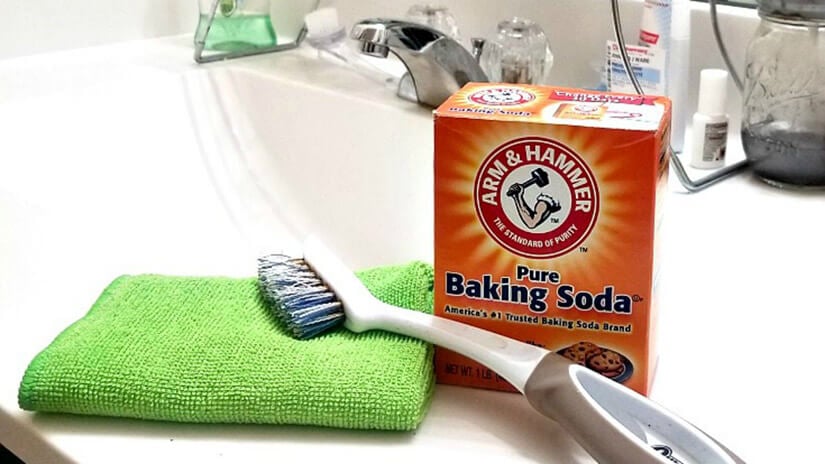 Using baking soda and a scrub brush to remove mold from grout.