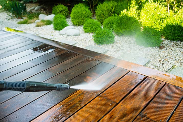 Using a pressure washer to clean deck.