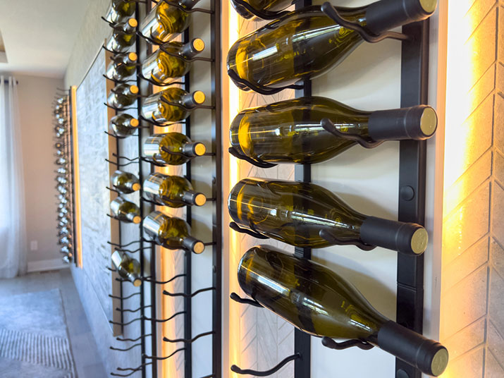 Wall-mounted metal peg wine rack displaying bottles horizontally.