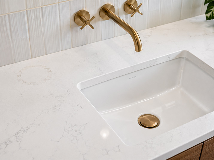 Clean countertop around a sink with a wall-mounted faucet showing no water spots or grime buildup at the faucet base.