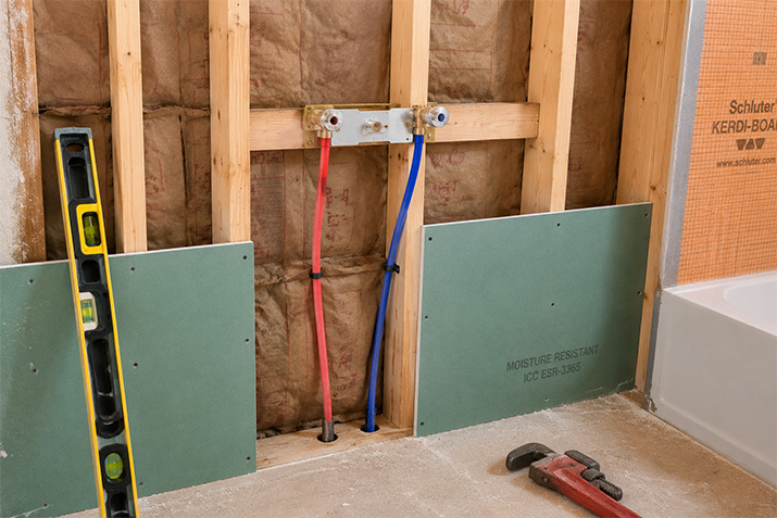 Exposed wall cavity showing in-wall plumbing rough-in for a wall-mounted faucet installation before drywall.