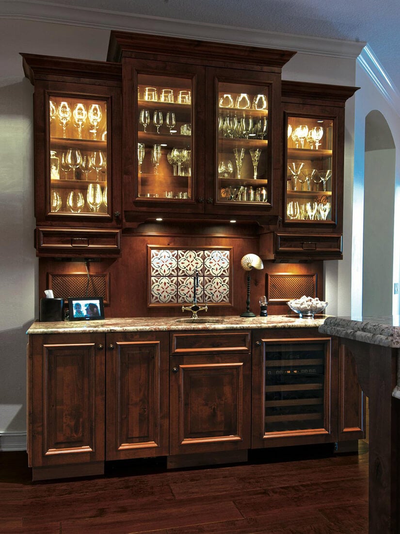 Wood built-ins and glass doors showcase glassware in this wet bar.
