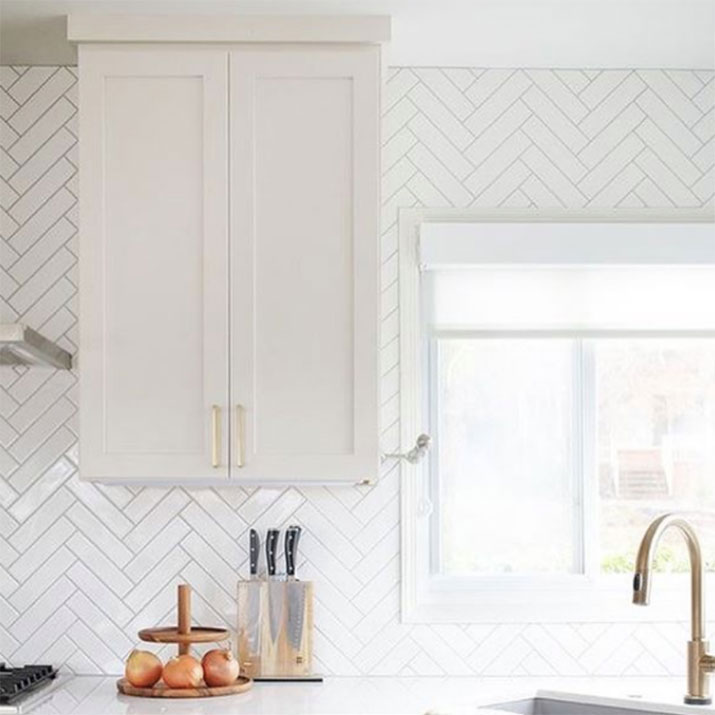 White herringbone subway tile backsplash with light gray grout.