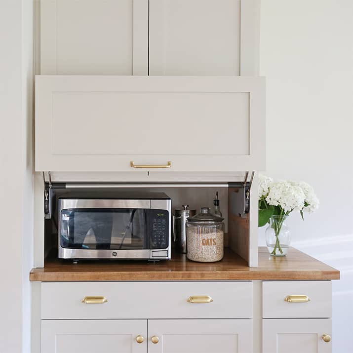 A white kitchen with an appliance hatch that hides the microwave.