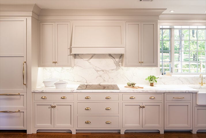 White kitchen with gold fixtures and white solid slab backsplash.