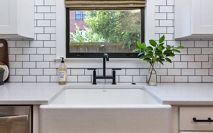 White kitchen with subway tiles surrounding window.