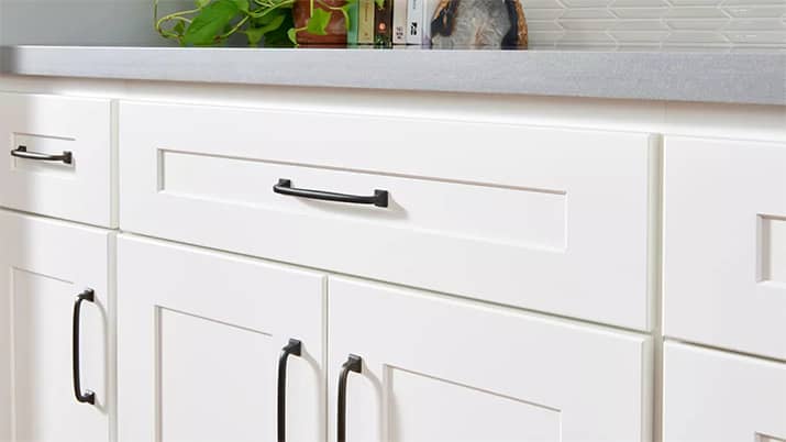 A white shaker cabinet with black arced handles.