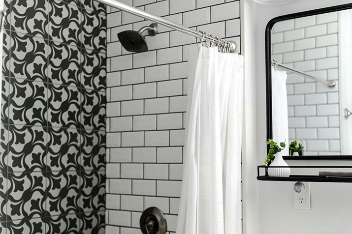 A white shower curtain in a black and white bathroom.