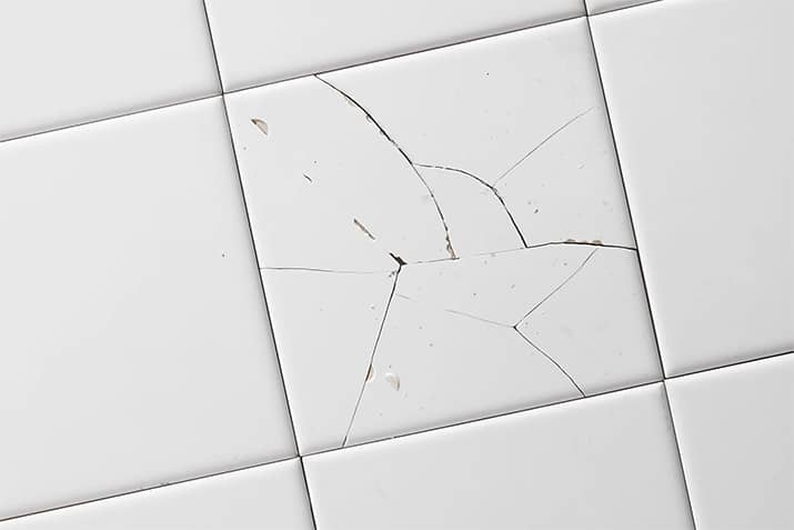 White tile with multiple cracks and white grout.