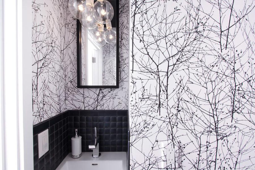 White and black bathroom wallpaper with wintry tree branches.