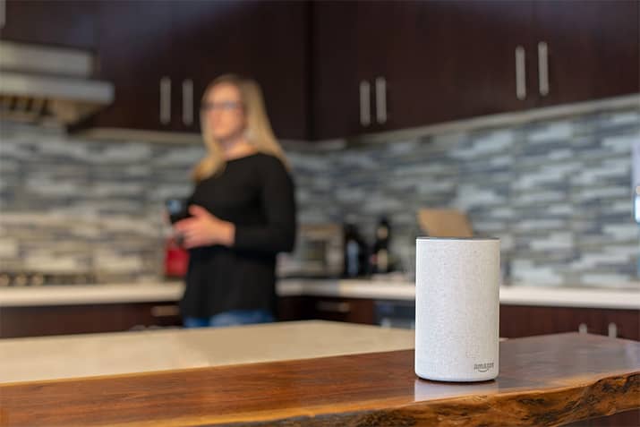 A woman in her kitchen with an Amazon Echo speaker.