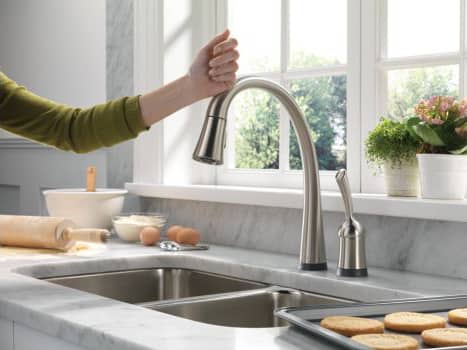 A woman turns the faucet of a touch-type kitchen sink with her wrist.