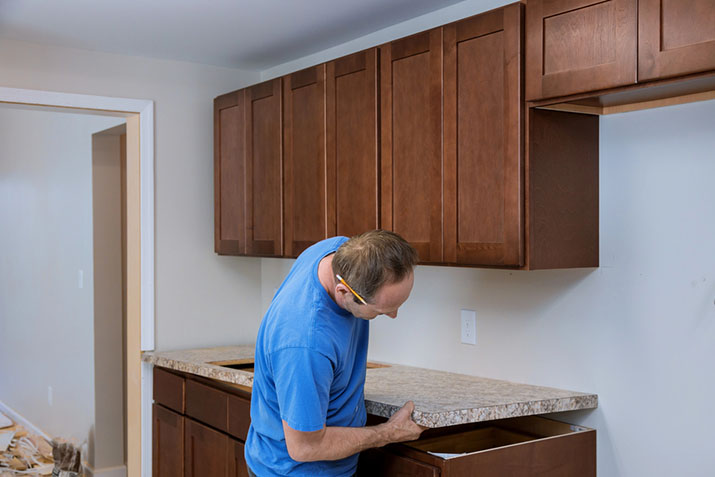 Worker putting countertops on in kitchen.
