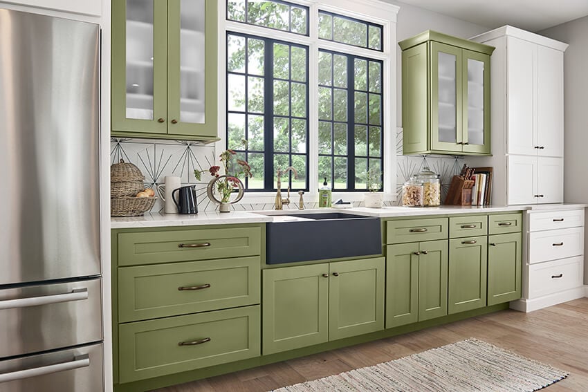 Bowery Laurel green cabinets with glass uppers and a black farmhouse sink