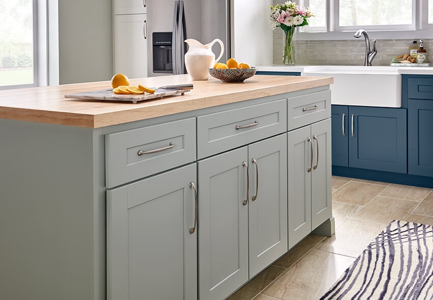 Bowery Palmetto island with a butcher block top beside blue lower cabinets