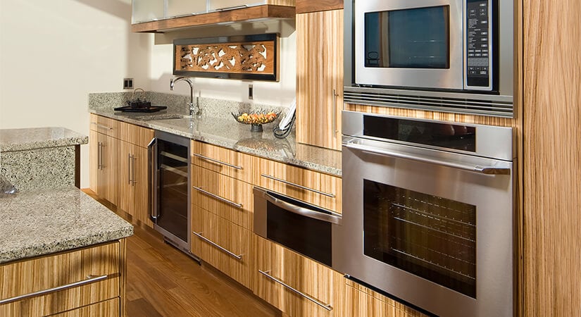 Modern kitchen with bamboo kitchen cabinets, silver hardware and granite countertops.