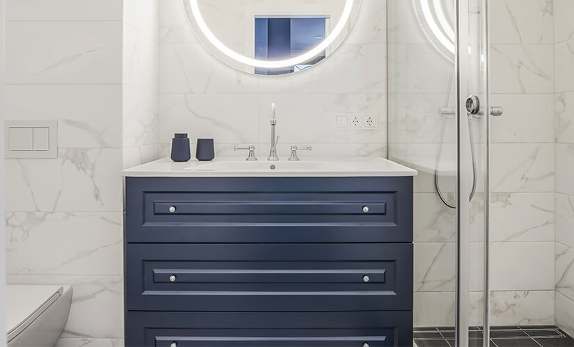 Small navy blue bathroom cabinet idea with marble wall tiles.