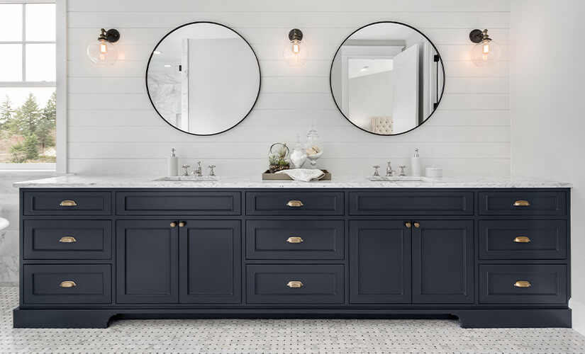 Bathroom with white walls and floor tile and large black vanity with brass hardware.