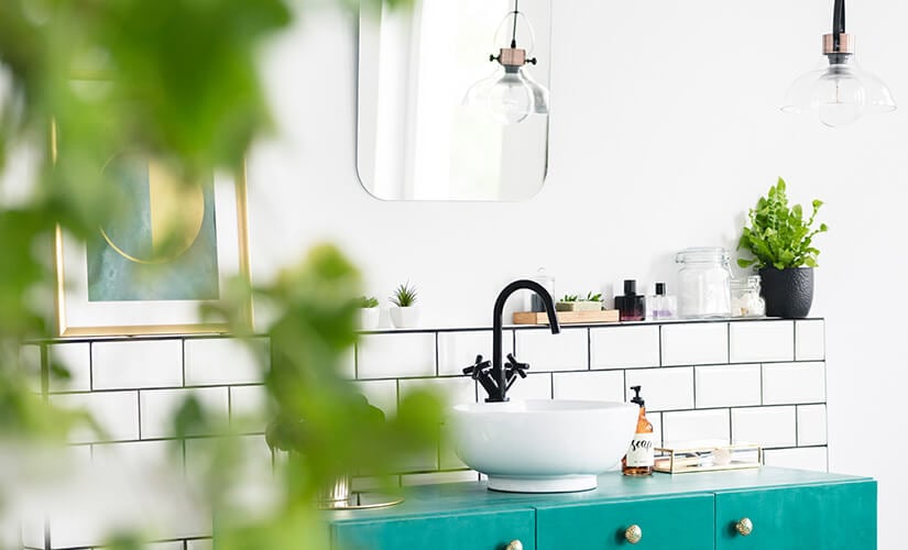 Bathroom with bright teal cabinets and white subway tile backsplash.