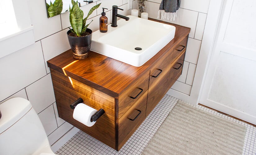Polished natural wood floating bathroom vanity with modern black hardware.