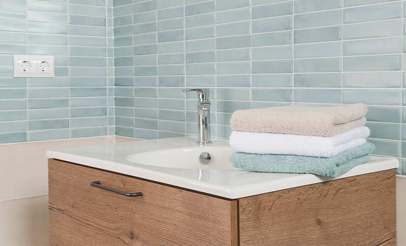 Small wood bathroom vanity with powder blue tile backsplash.